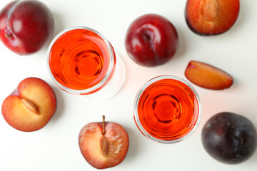Plum brandy shots and ingredients on white background