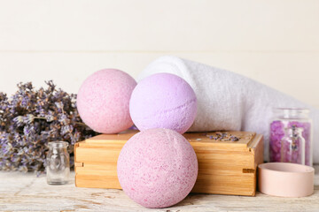 Composition with bath bombs, sea salt, towel and lavender flowers on light wooden background