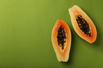 Halves of ripe papaya on green background
