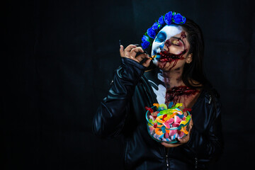 Halloween Catrina Zombie Eating colored sweets. Halloween costume and makeup.