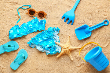 Fototapeta na wymiar Set of beach accessories for children and stylish swimsuit on sand