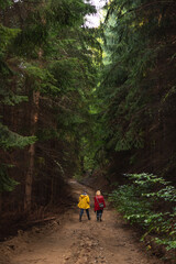 Middle age couple in raincoats walking through forest