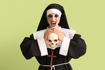 Woman dressed for Halloween as nun with skull on color background