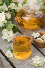 Green Chinese tea with jasmine in a mug with jasmine flowers.