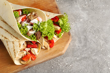 Wooden board with tasty Fajitas on grunge background, closeup