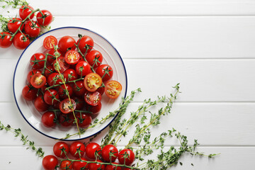 Composition from a plate full of branches of ripe fresh cherry tomatoes with spices on a wooden background