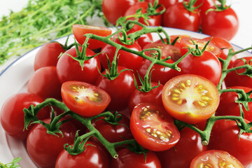 Composition from a plate full of branches of ripe fresh cherry tomatoes with spices on a wooden background