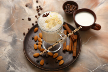 Glass cup of tasty almond latte on grunge background