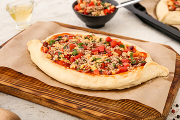 Wooden board with uncooked Turkish Pizza on white background