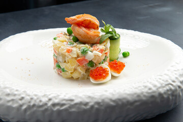 Traditional Russian salad with egg, peas, potatoes and mayonnaise on a plate.