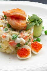 Traditional Russian salad with egg, peas, potatoes and mayonnaise on a plate.