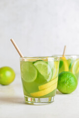 Glasses with tasty green lemonade on light background
