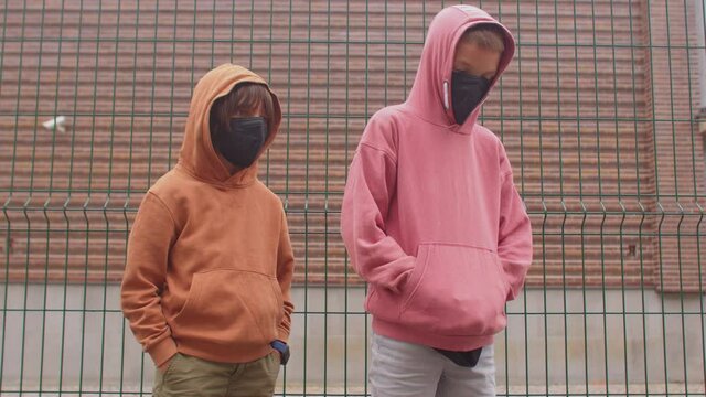 A portrait of teenagers in black face masks and in a hoodie. Self-expression of teens using clothes. Adolescents use friends and fashion to bolster their self-esteem through mirroring and twinship.