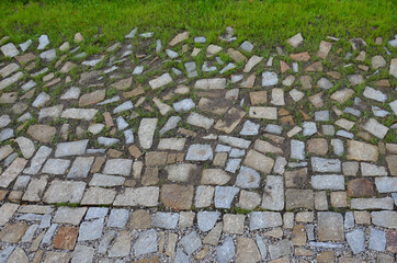 transition of paved surfaces between paving and lawn. the lawn grows between individual randomly placed stones of granite chipped paving. full to very loose texture