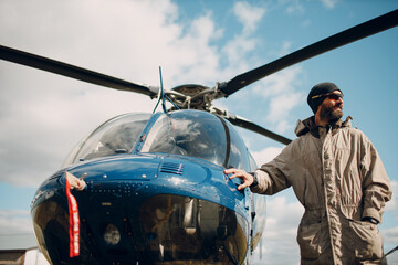 Portrait of helicopter pilot standing near vehicle in field airport. © primipil
