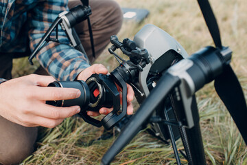Man pilot checking quadcopter drone and putting on camera lens before aerial flight and filming