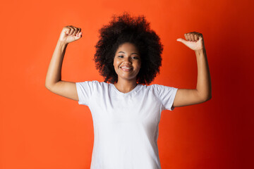 beautiful african woman in white t-shirt with raised arms on red background 