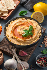 Hummus and ingredients on a dark background. A traditional oriental snack. Side view, close-up.
