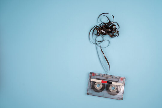 Cassette tape over wooden table with tangled ribbon. top view. retro filter