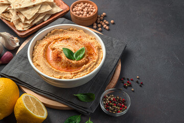 Oriental hummus with sesame, lemon and garlic on the background of ingredients. Healthy, vegetarian food. Side view, space for copying.