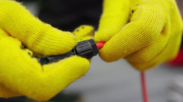 An electrician checks the wires. Special wire hardener at the power plant. An electrician in protective gloves installs wires. Connection of soy panels