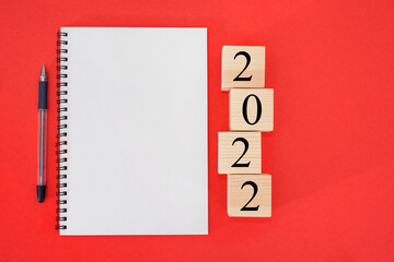 2022 is the time for a fresh start. Word plan and 2022 cubes on a red background. New Year. plans for 2022, place for text in notepad, calendar mockup