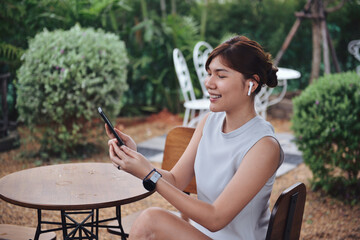 Young woman talking in video chat via digital mobie and white wireless .while sitting in her favorite garden