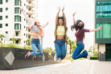 Three exuberant young woman leaping into the air together - obrazy, fototapety, plakaty