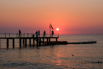 Beautiful sunset sunrise beach with pink sky and pier. Travel, relax and meditation concept. Mediterranian sea