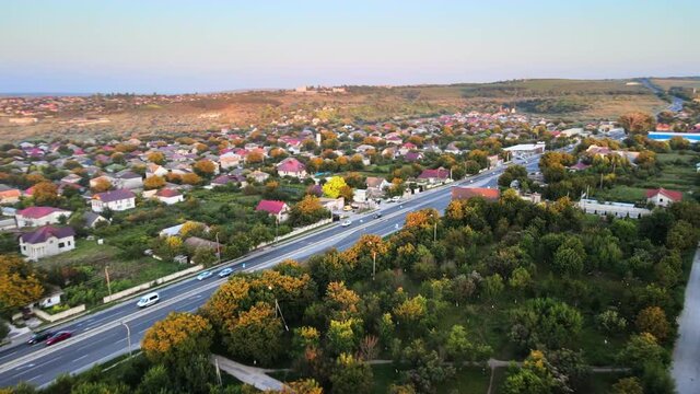Aerial drone view of Tipova, Moldova at sunset. Road with cars, residential buildings, greenery