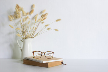 Books with glasses with flowers over the white background. 