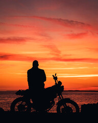 Fototapeta premium silhouette of a biker on a motorcycle, orange and pink sunset with text space copy space