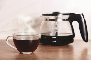 Hot coffee in glass cup and jug of coffee maker