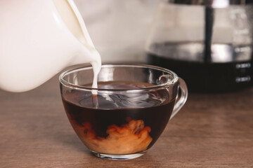 Milk is poured into glass coffee cup