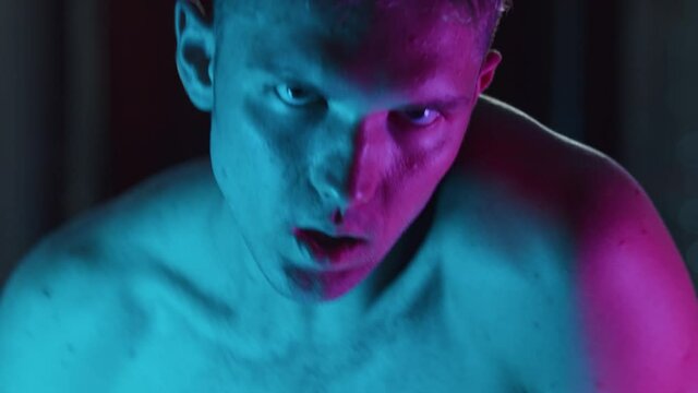 A young man stripper acting sexy in neon lighting