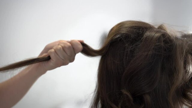 hairdresser makes a hairstyle for a girl with dark hair