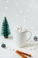 Obraz na płótnie Canvas close-up of a white cup with a drink and marshmallows against the backdrop of christmas decor on a white background