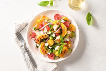 Piquant Panzanella with tomatoes, bread, cheese and grilled peach in plate on white background. Top view. Italian cuisine. Vegetarian panzanella salad. Summer vegetables colorful salad.