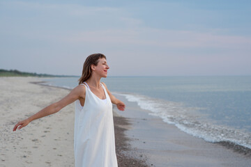 Fototapeta na wymiar Woman dancing in white dress near the sea