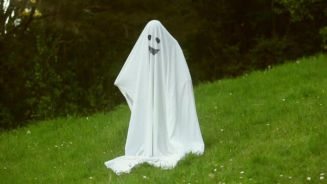 child dressed up as ghost for halloween, kid costume of a ghost, outdoor shoot, natural background. 