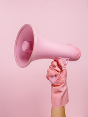 A woman's hand in sanitary gloves holding a pink megaphone isolated on a pink background. People sincere emotions lifestyle concept. Time of propaganda, protest, and loud speaking. Advertisement idea