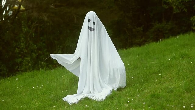 child dressed up as ghost for halloween, kid costume of a ghost, outdoor shoot, natural background. 