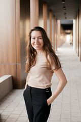 Fototapeta na wymiar Young millennial businesswoman standing near office building and smiling