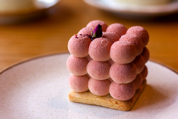 delicate Pink velours Moose cakes  in the shape of a cube of balls decorated with a rose on a saucer close-up