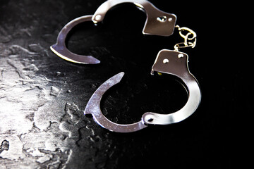Police metal real handcuffs on the black background. Crime and robbery, prison concept.