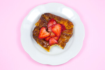 Bitten Puff pastry bun or roll. Cake with fresh strawberries. Delicious sweets temptation and...