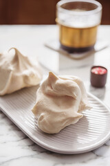 Homemade sweet meringue cookies and cup of coffee on white marble table. Delicious and light dessert. Selective focus