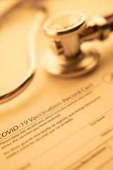 Vertical Photography of a Covid-19 Vaccination Card and Stethoscope