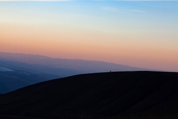 Landscape in the mountains at sunset. View of the misty hills hidden behind the oncoming darkness