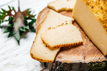 Cut cheese with spices on a white background. pieces of hard yellow Dutch gouda cheese. Holland cheese
